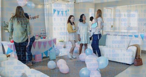 Women celebrating baby shower at home holding infants with pastel balloons and cake