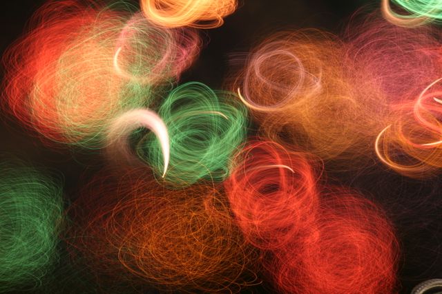 Colorful light bokeh with vibrant red, green, and orange swirls, creating festive and lively atmosphere. Ideal for holiday design elements, backgrounds for parties, festive seasons, events, or creative projects requiring radiant patterns and vivid colors.