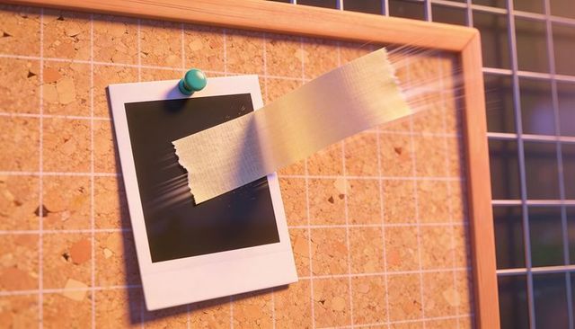 Blank instant film print pinned and taped on cork bulletin board with green thumbtack