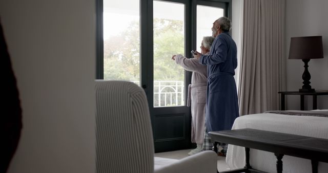 Elderly Couple in Robes Enjoying Morning View from Bedroom Window - Download Free Stock Images Pikwizard.com