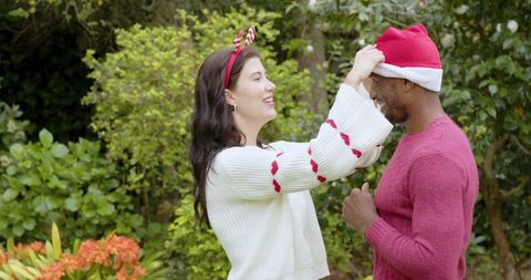 Joyful couple celebrating with santa hat and antler headband in garden