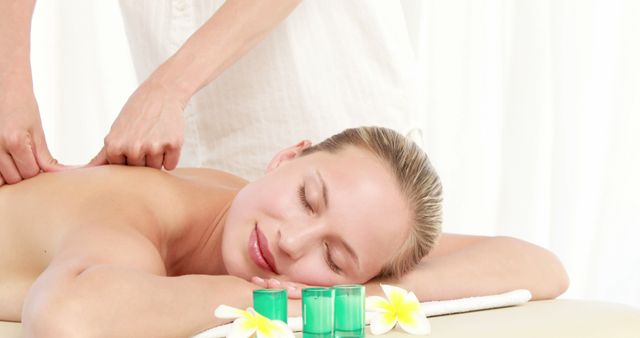 A Caucasian woman enjoys a relaxing massage from a masseuse, with copy space. The serene setting suggests a spa environment, emphasizing wellness and self-care.