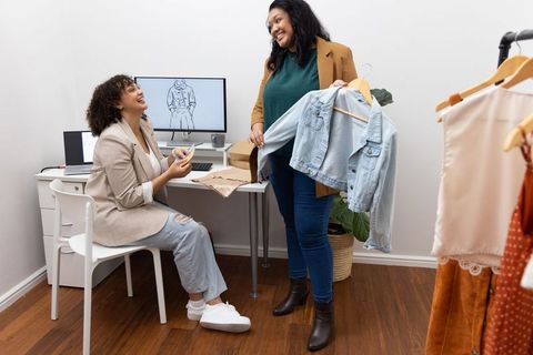 Boutique fashion designers collaborating over denim jacket and fabric swatches