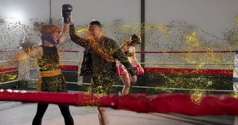 Referee raising glove for victorious boxer amid gold glitter celebration in ring