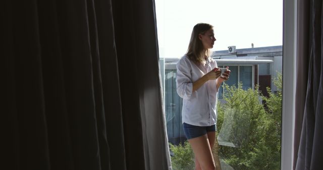 Young Woman Drinking Coffee by Sunny Window in Casual Clothing - Download Free Stock Images Pikwizard.com