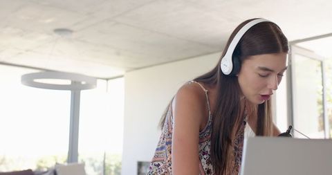 Focused Teenage Girl with Headphones Studying on Laptop