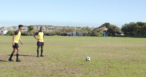 Soccer Players Strategizing on Sunny Field for Free Kick
