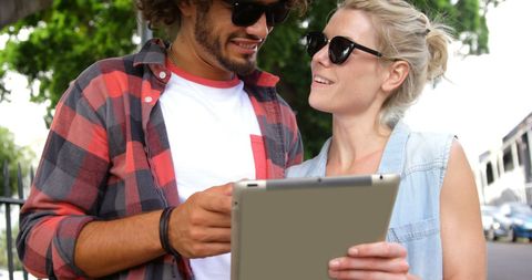 Two Friends Chatting and Sharing Tablet Outdoors