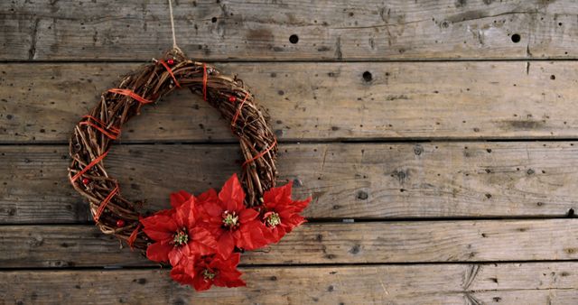 A festive Christmas wreath with red poinsettias enhances the cozy ambiance on a wooden backdrop. - Download Free Stock Photos Pikwizard.com