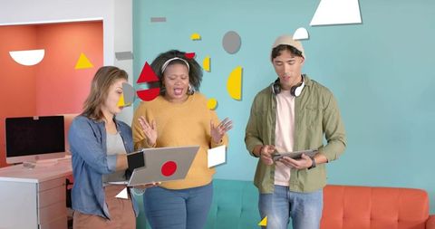 Creative team collaborating in colorful lounge with laptop and tablet for digital marketing