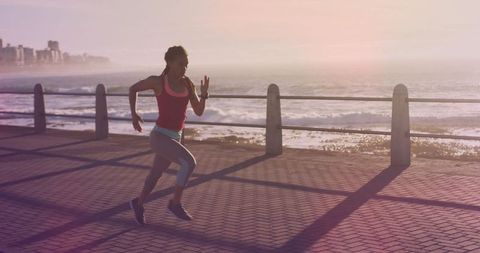 Energetic Woman Running at Sunrise on Scenic Promenade