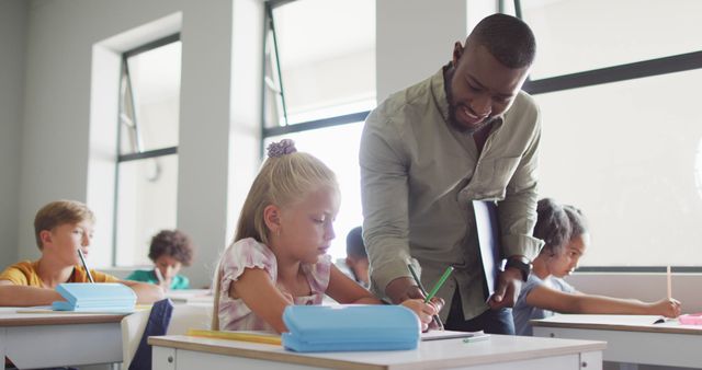 Image of happy african american male teacher helping in exercise to caucasian girl - Download Free Stock Photos Pikwizard.com