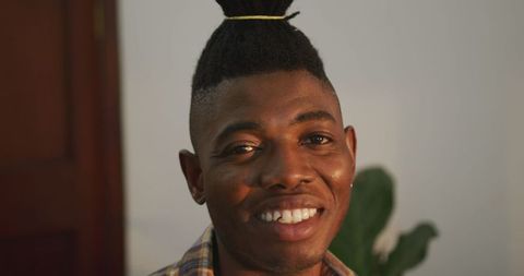Confident Smiling Man with Stylish Updo in Cozy Home