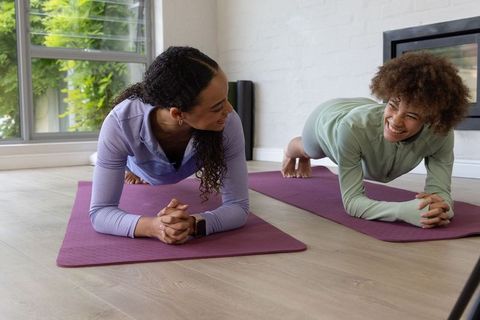 African american friends doing forearm planks on purple mats, core strength and smile