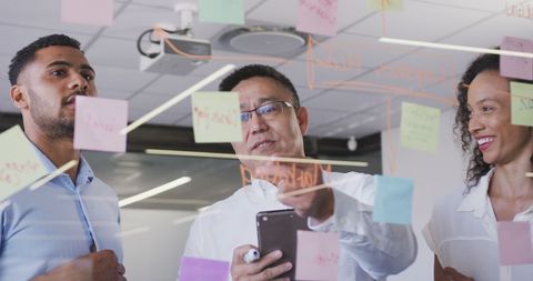 Diverse Team Collaborating with Notes on Glass Wall in Office