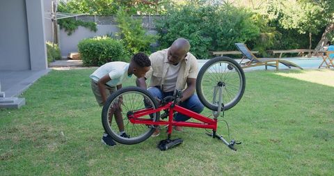 Father and Son Repair Bicycle Together in Backyard