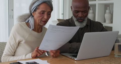 Older Couple Managing Finances with Laptop and Documents at Home