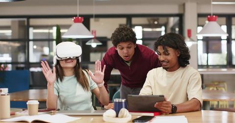 Young African students testing VR headset and collaborating with tablet in modern coworking hub
