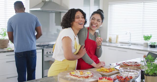 Happy diverse male and female friends making pizza, cooking in kitchen, in slow motion. Friendship, cooking and lifestyle concept.