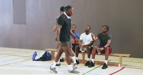 African american players greeting bench mates, grabbing gear and walking off indoor court