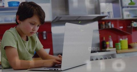 Young boy typing on laptop at kitchen counter studying from home with focused expression
