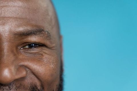 African american senior man smiling gently, turquoise closeup portrait conveying warmth