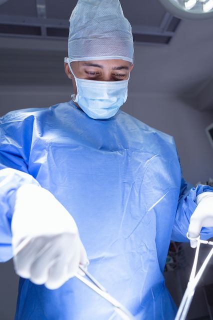 Low angle view of male surgeon performing surgery operation room at hospital