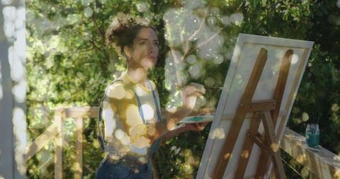 Hispanic Woman Painting on Sunlit Deck Outdoors