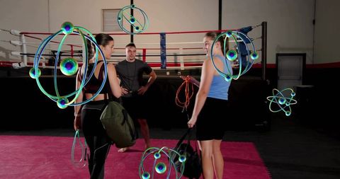 Female athletes and coach training in boxing ring carrying duffel bags with holographic orbits