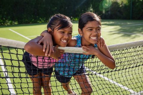Cheerful Girls Enjoy Outdoors on Tennis Court