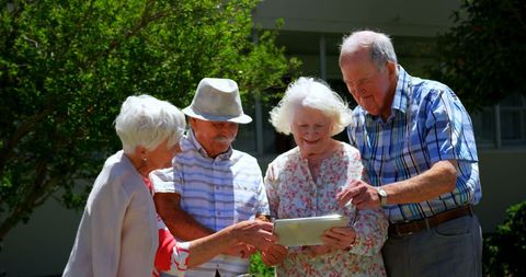 Senior Couples Engaging with Digital Tablet in Garden