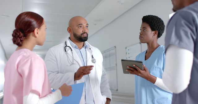 Multicultural doctors and nurses standing in hospital corridor, engaged in serious discussion about patient care, showcasing teamwork and communication. Ideal for use in healthcare and medical related content, hospital teamwork features, and recruitment materials for medical staff.