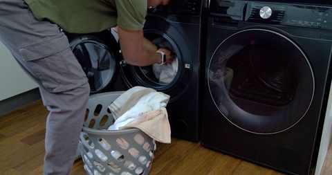 Man loading laundry into front-loading washing machine in modern laundry room