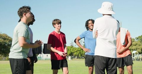 Youth cricket team receiving coaching during sunny outdoor training session