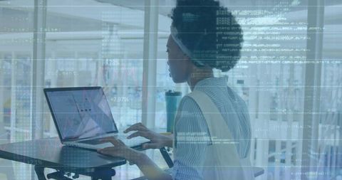 Woman analyzing data on laptop at standing desk with analytics overlay in modern office
