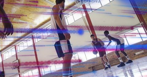 Basketball players practicing dribbling in gym with dynamic light effects