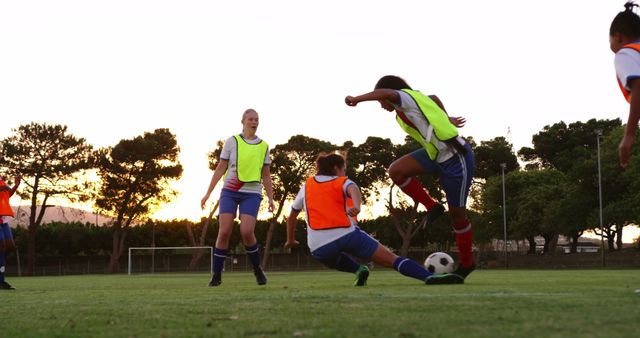 Youth players competing in an outdoor soccer match at sunset. Great for showcasing youth sports, teamwork, competitive spirit, athletic events, and sporting activities in natural settings.
