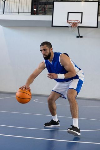 Basketball Player Dribbling Ball on Indoor Court