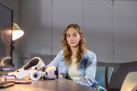 Young woman sitting at desk testing vr headset in modern minimalist home office workspace