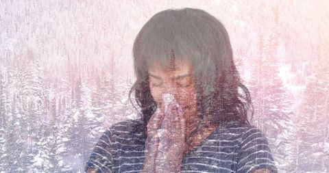 Woman sneezing with overlay of winter scenic background