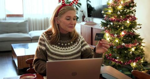 Festive Senior Woman Online Shopping by Christmas Tree