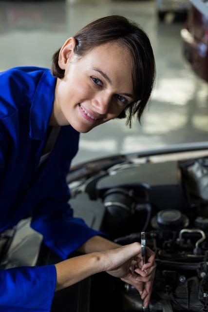 Female mechanic smiling while servicing a car in repair garage
