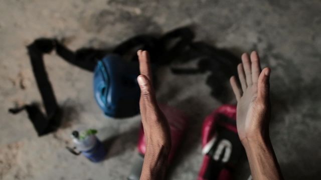 Hands of a biracial man throwing chalk while clapping in gym near equipment, including protective helmet, emphasizes athletic dedication and physical exercise. Ideal for fitness content, motivational materials, and health-related blogs appealing to viewers interested in sports and training.