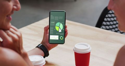 Team Analyzing Data on Smartphone Screen in Modern Office Cafe
