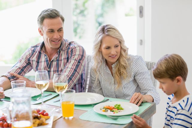Parents interacting with son on dining table at home
