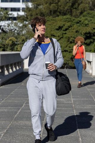 Diverse commuters walking and talking on phone on sunlit urban pedestrian bridge