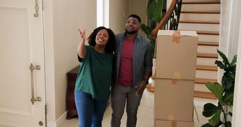 Cheerful couple moving into new home with cardboard boxes
