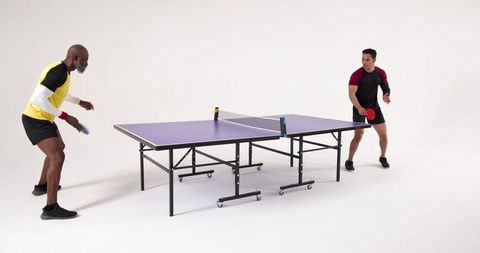 Athletic men competing in intense table tennis match