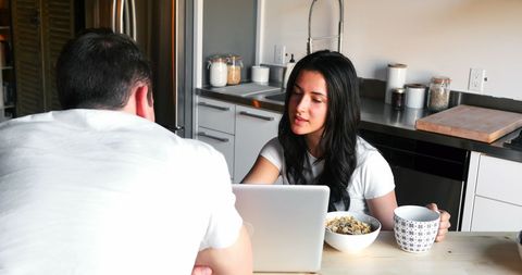 Couple Having Breakfast While Using Laptop in Modern Kitchen