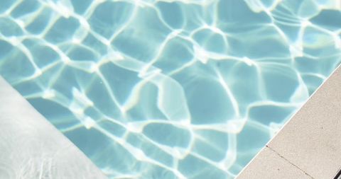 Sunlit turquoise pool corner with shimmering caustic ripples, concrete step and deck